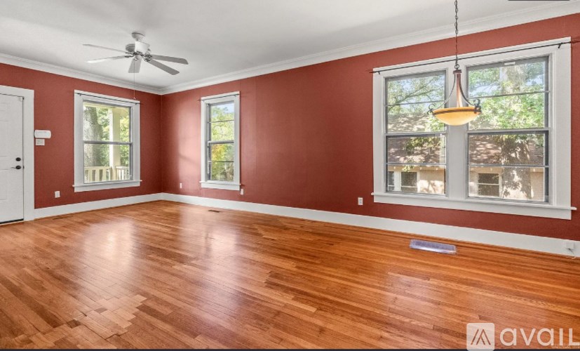 A room with red walls and wooden floors is available for rent.
