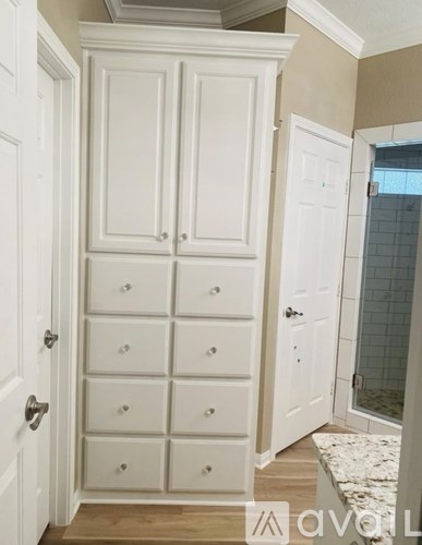 A tall white cabinet with drawers is in a room.