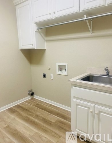 A kitchen with white cabinets and a wooden floor.