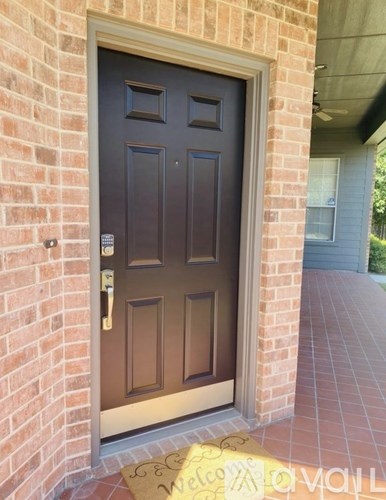 A brown door with a gold handle and a welcome mat in front of it.