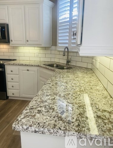 A kitchen with a marble countertop and white cabinets.