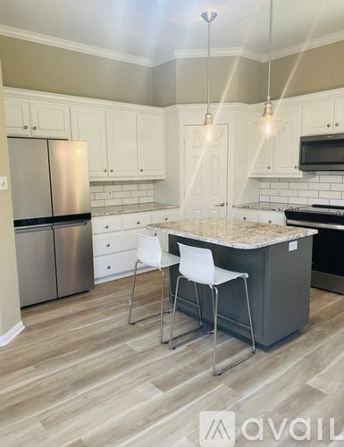 A kitchen with a marble countertop and white cabinets.