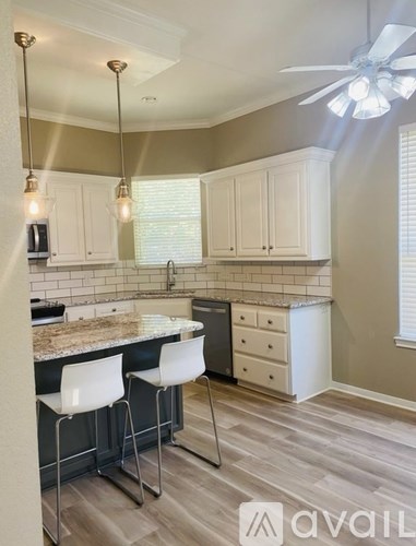A kitchen with a marble countertop and white chairs.