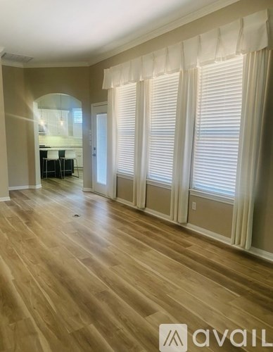 A room with wooden floors and white curtains.