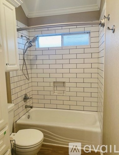A white toilet is next to a bathtub in a bathroom with white tiles.