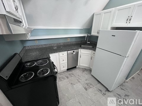 A kitchen with a black stove top and a white refrigerator.