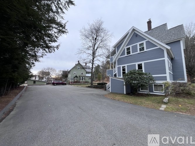 A blue house with a grey roof and a white car parked in front.
