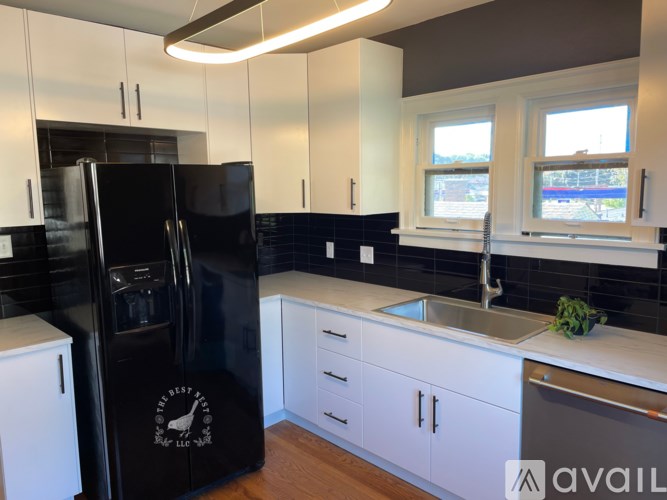A black fridge in a kitchen with white cabinets.