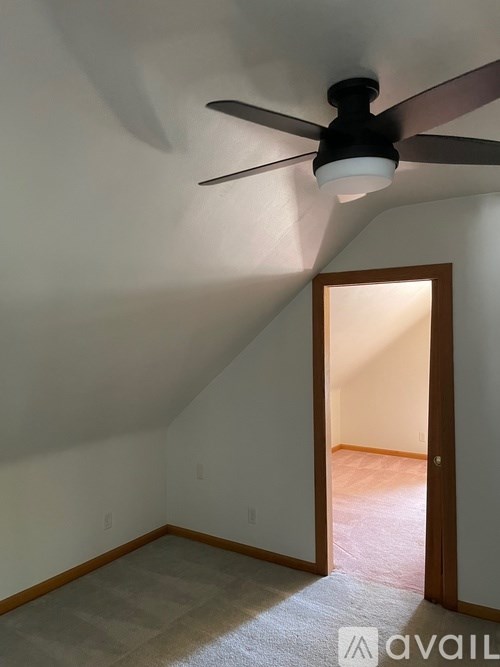 A room with a ceiling fan and a door leading to another room.