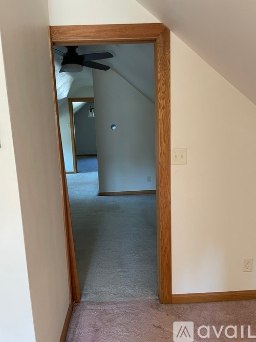 A hallway with a wooden door frame and a ceiling fan.