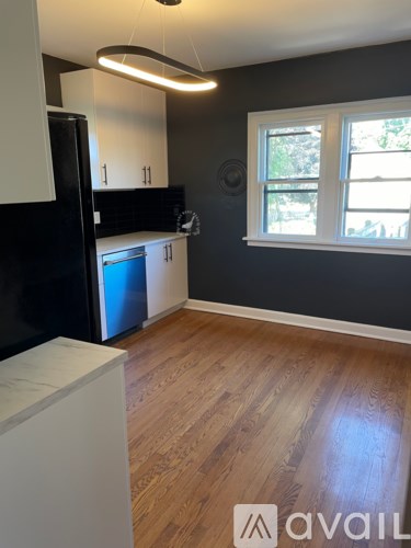 A kitchen with a black refrigerator, white cabinets, and a wooden floor.