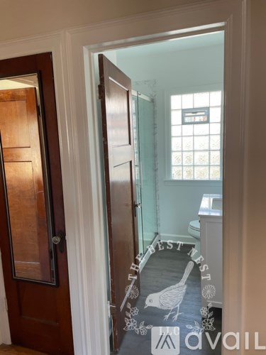 A hallway with a wooden door and a glass door leading to a bathroom.