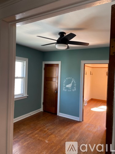 A room with a ceiling fan and wooden floors.