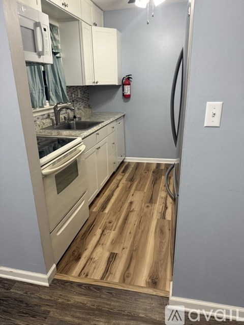 A kitchen with white cabinets and a wooden floor.