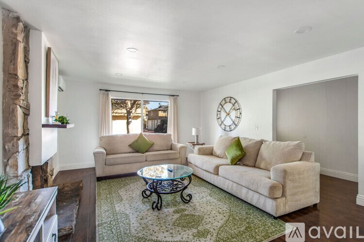 A living room with a couch, a coffee table, and a clock on the wall.