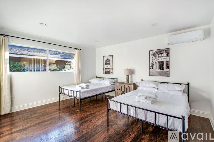 Two twin beds in a room with wooden floors and white walls.