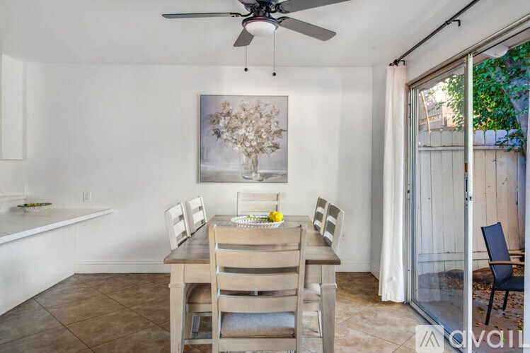 A dining room with a table set for two and a painting on the wall.