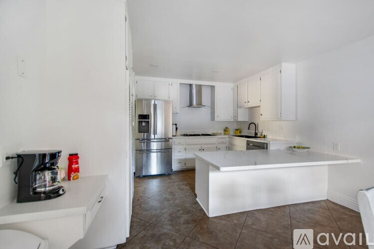 A kitchen with white cabinets and a white island.