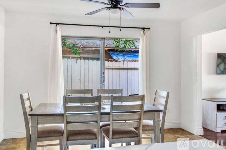 A dining room with a table and chairs and a ceiling fan.