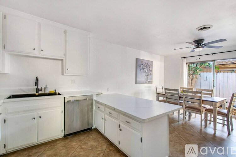 A kitchen with white cabinets and a dining table with chairs.