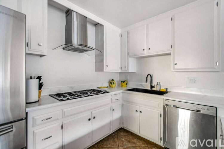 A kitchen with white cabinets and a stainless steel refrigerator.