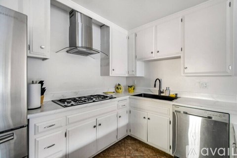 A kitchen with white cabinets and a stainless steel refrigerator.
