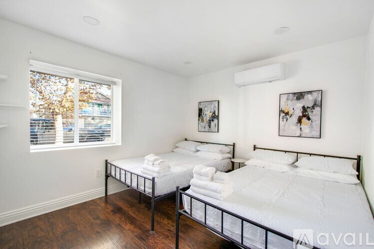 Two twin beds in a room with white walls and wood floors.