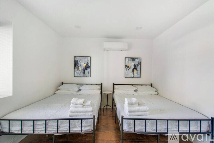 Two twin beds with white bedspreads and towels on them in a room.
