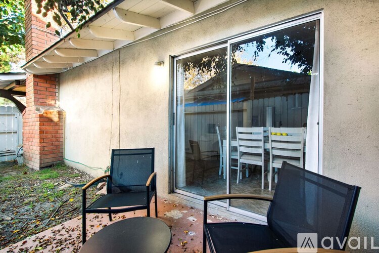 A patio with a black chair and table in front of a house.