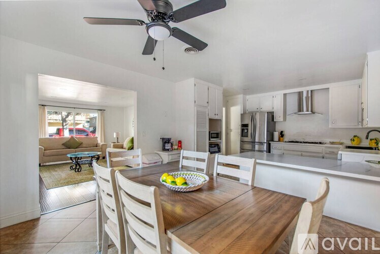 A kitchen with a table and chairs in the foreground and a fan on the ceiling.