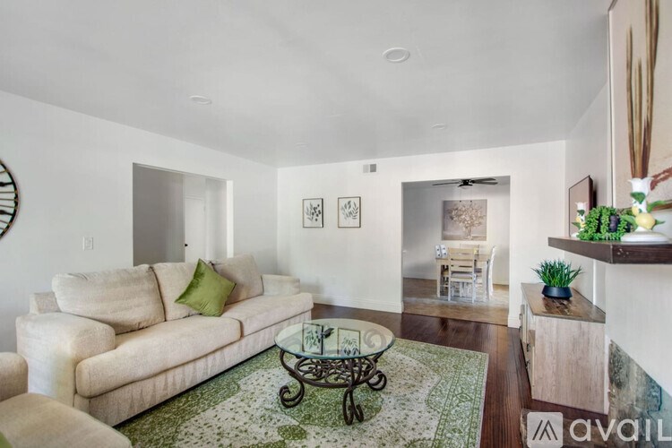 A living room with a beige couch and a green throw pillow.