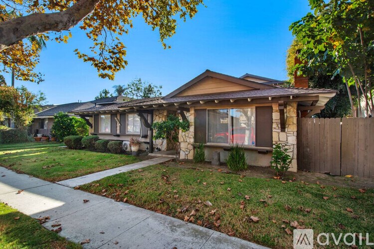 A house with a brown roof and a white fence is for sale.