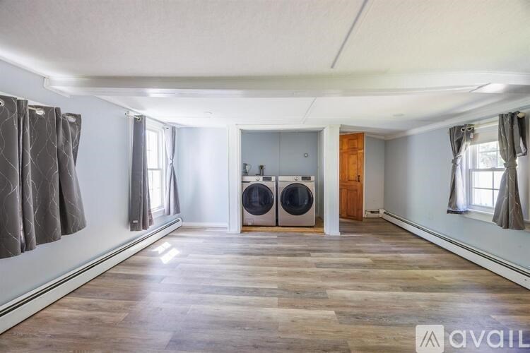 A spacious room with wooden flooring and a washing machine in the corner.