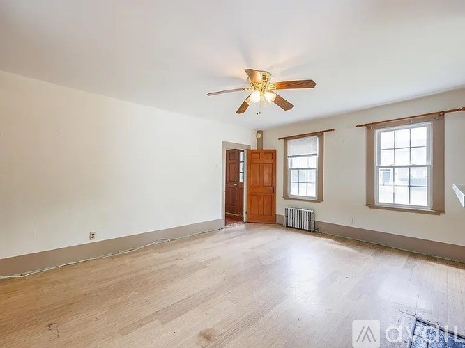 A room with a ceiling fan and wooden flooring.
