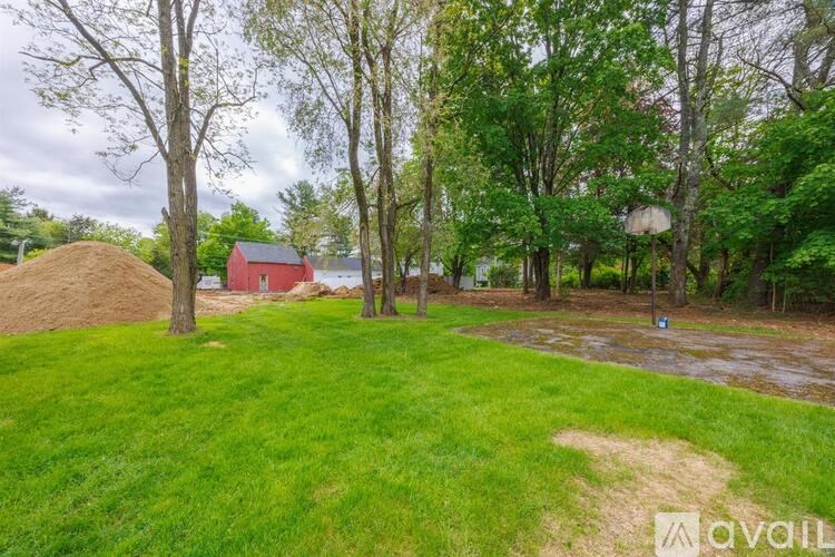 A grassy area with trees and a red building in the background.