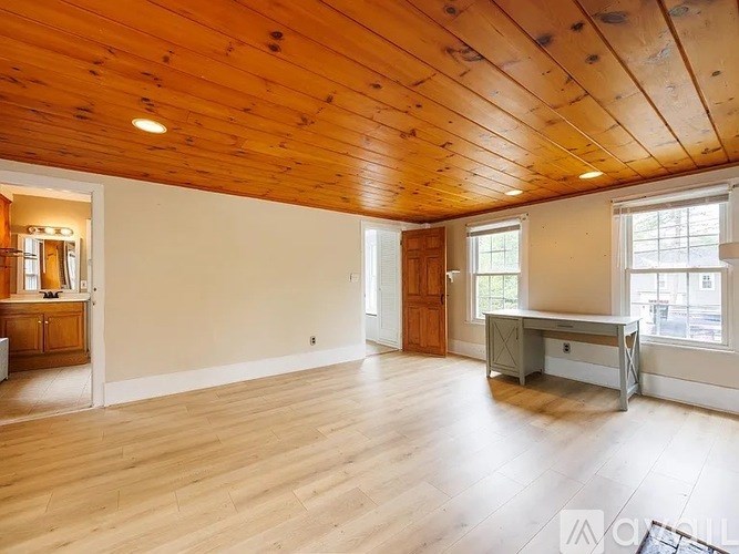 A spacious room with wooden floors and a high ceiling.