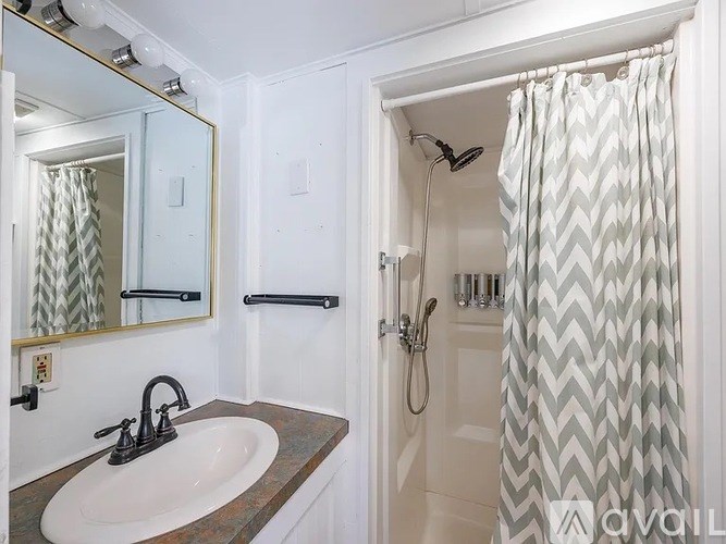 A bathroom with a sink, mirror, and shower.
