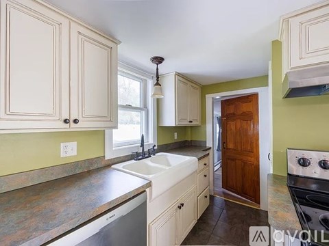 A kitchen with white cabinets and a green wall.
