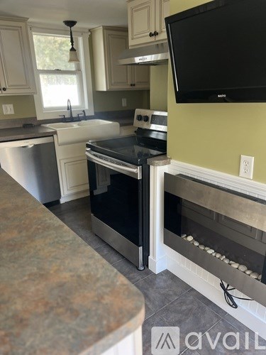 A kitchen with a black oven and a black TV mounted on the wall.