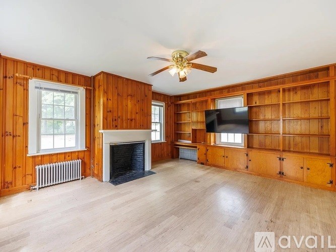 A living room with wood paneling and a fireplace.