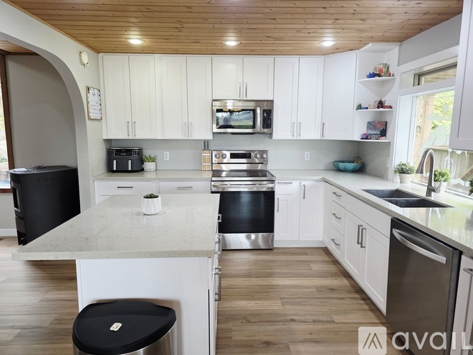 A kitchen with white cabinets and a wooden ceiling.