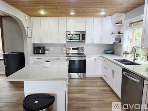 A kitchen with white cabinets and a wooden ceiling.
