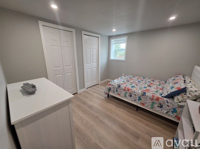 A bedroom with a bed, dresser, and two doors.