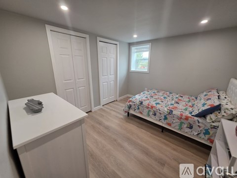 A bedroom with a bed, dresser, and two doors.