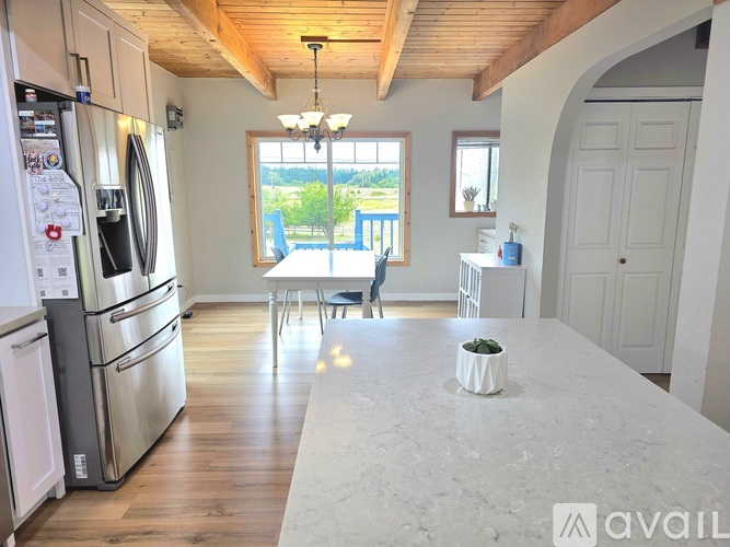 A kitchen with a refrigerator, oven, and a dining table with chairs.
