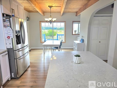A kitchen with a refrigerator, oven, and a dining table with chairs.
