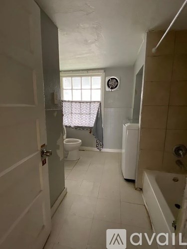 A bathroom with a toilet, a window, and a bathtub.
