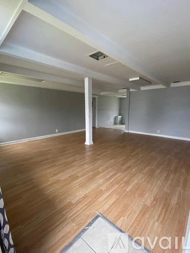 A room with wooden flooring and white walls.