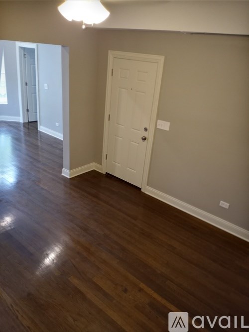 A room with a white door and wooden flooring.