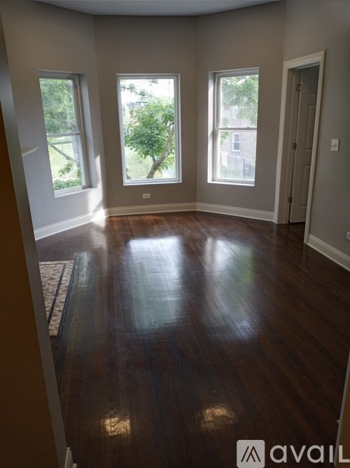 A room with wooden floors and three windows.